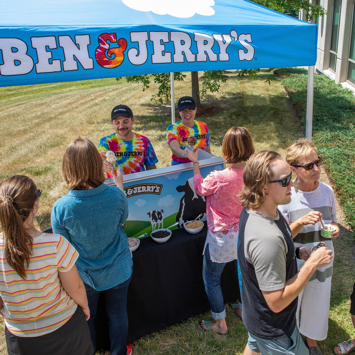 Heladeros de Ben & Jerry’s sirviendo cucuruchos de helado a un grupo de personas